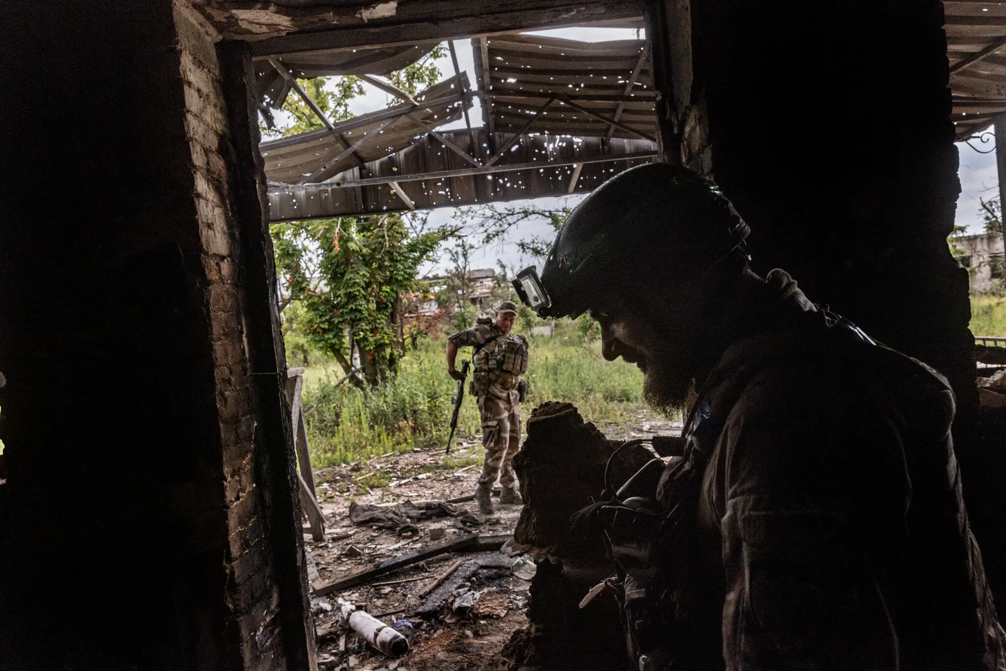 Українські військові проходять через головний вхід зруйнованої школи, яку зайняли російські війська в нині покинутому селі Нескучне, Україна, 28 червня.